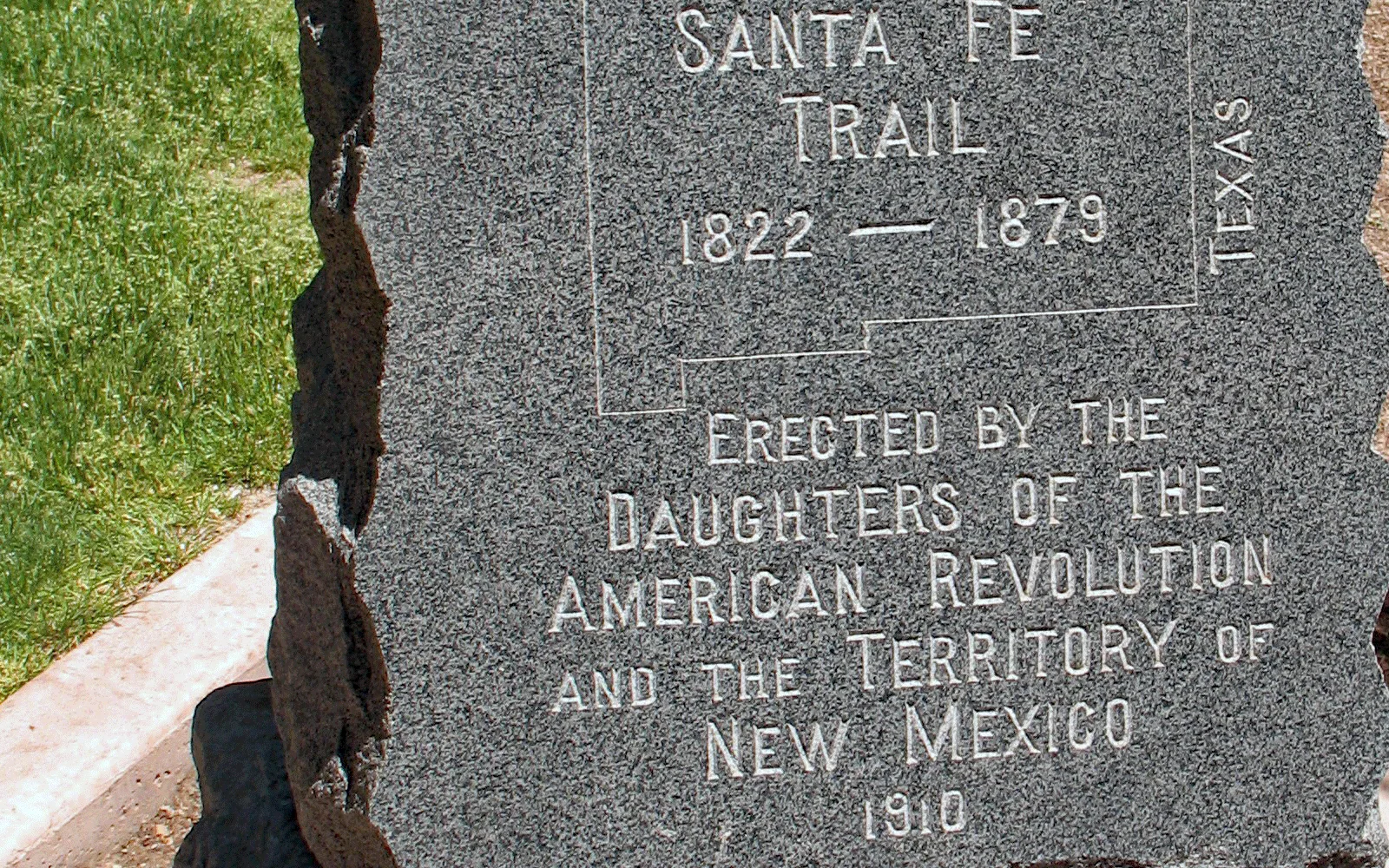 Stone monument marker labeled 'End of Santa Fe Trail' against architectural background